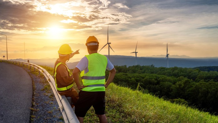 Two human beings in front of a wind plant